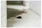 A red extension cord with a black plug lies on a dusty concrete floor in an unfinished room.<br>