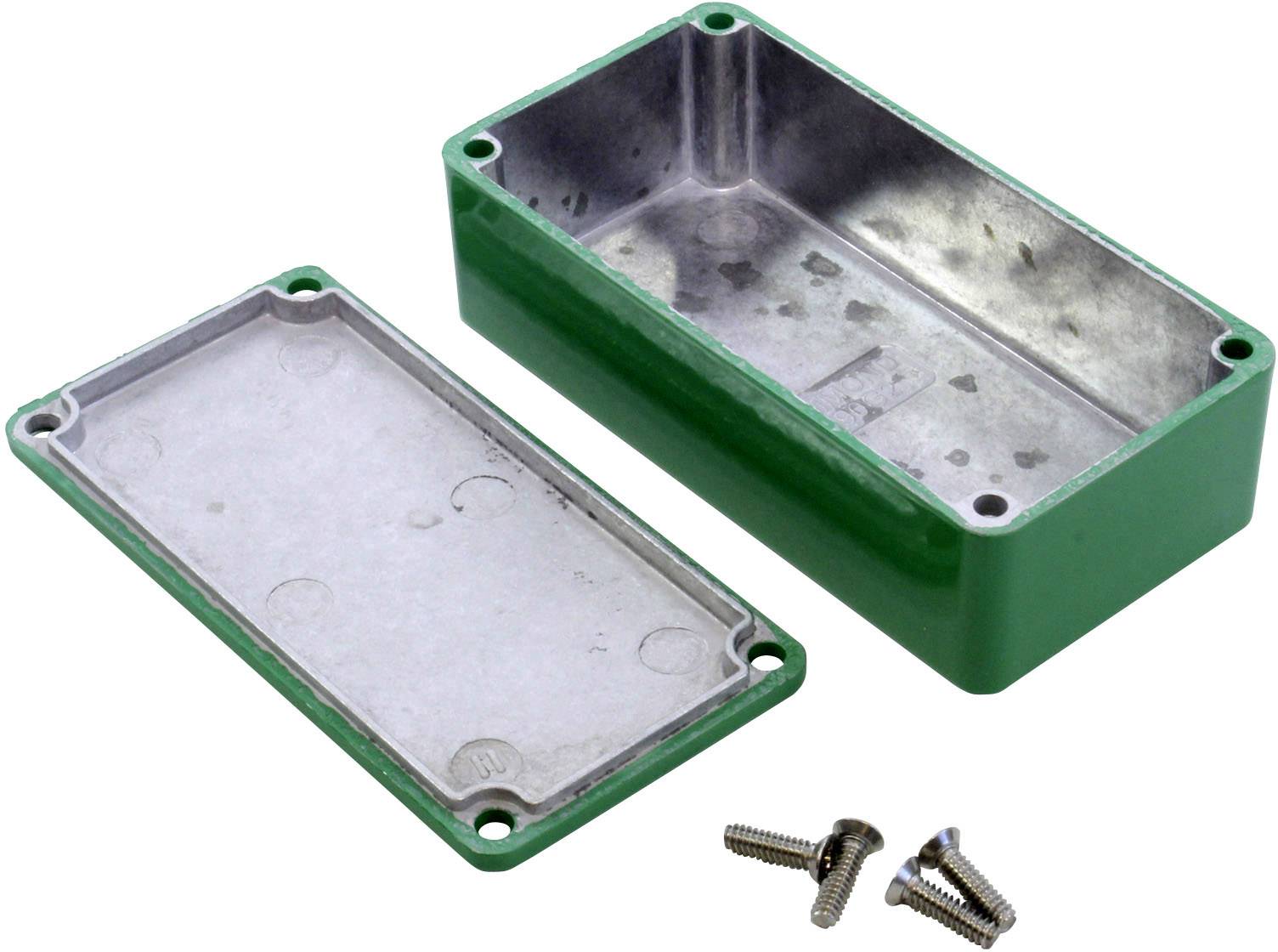 Green rectangular metal casing with removed lid reveals inner chamber. Four screws are lying beside it.