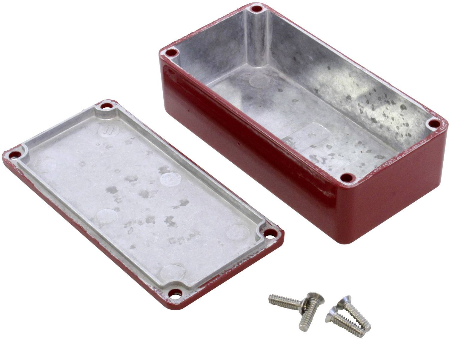 Rectangular red metal casing with its cover removed; three loose screws in front of it.