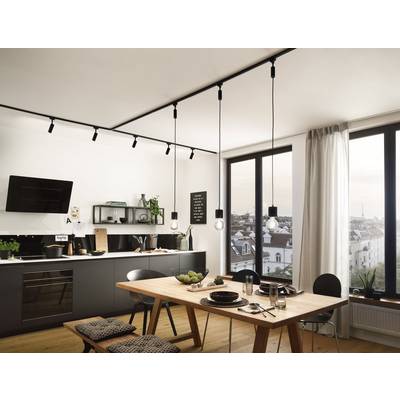 Modern kitchen with light walls, a wooden dining table, hanging lamps, and a view of urban rooftops through large windows.