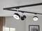 Black track lighting system with three round, adjustable ceiling lights on a white ceiling in a modern interior space.