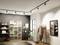 A stylish showroom with a mannequin, clothing rails with elegant garments, shelves with folded clothing, and a large mirror.