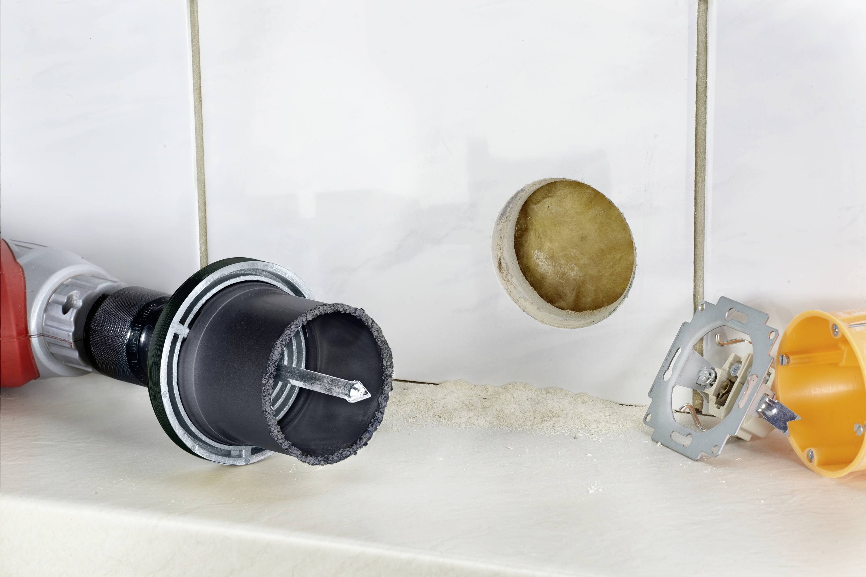 'Tool for drilling tiles next to a drilled tile and socket components'; shows DIY supplies and renovation process.