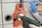 A person is using a drill with a dust extraction system on a tiled wall to capture dust and dirt.