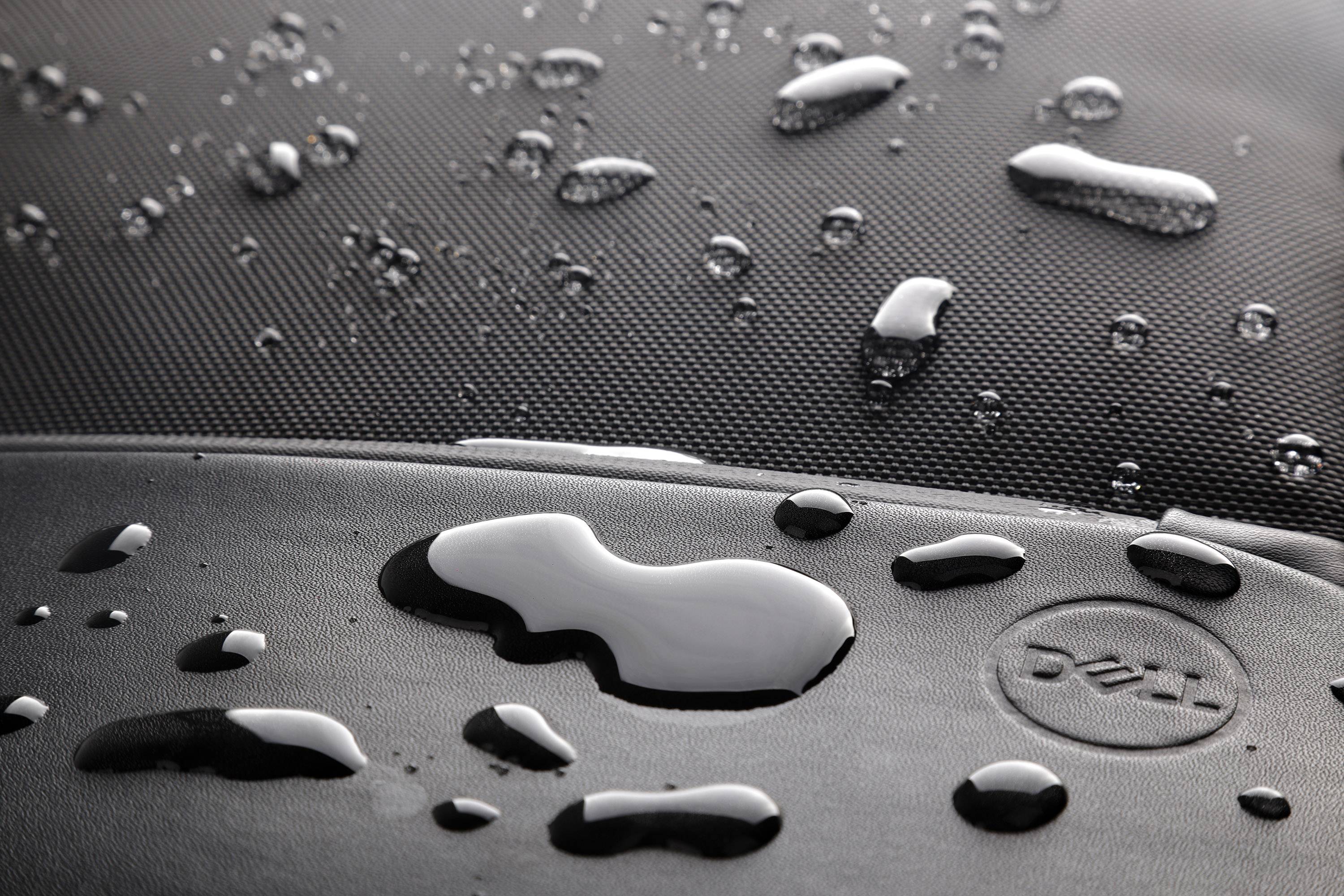 Water droplets on a textured surface, with their reflective properties and patterns standing out prominently.