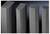 Four large, dark, rectangular pillars of varying heights stand side by side against a dark background.