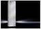 A tall, gleaming silver radiator stands on a glossy black background with a light reflection from the right.