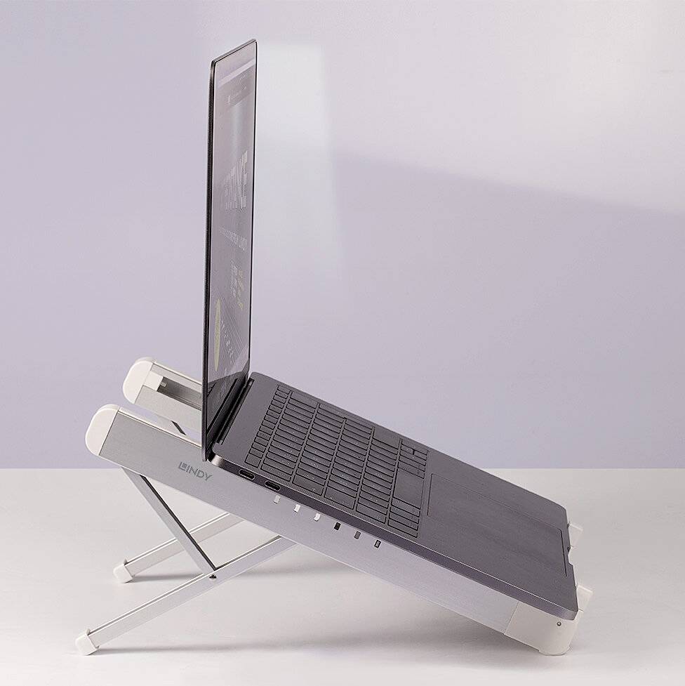 A laptop is positioned at an angle on an adjustable stand. The screen displays slightly blurry contents.