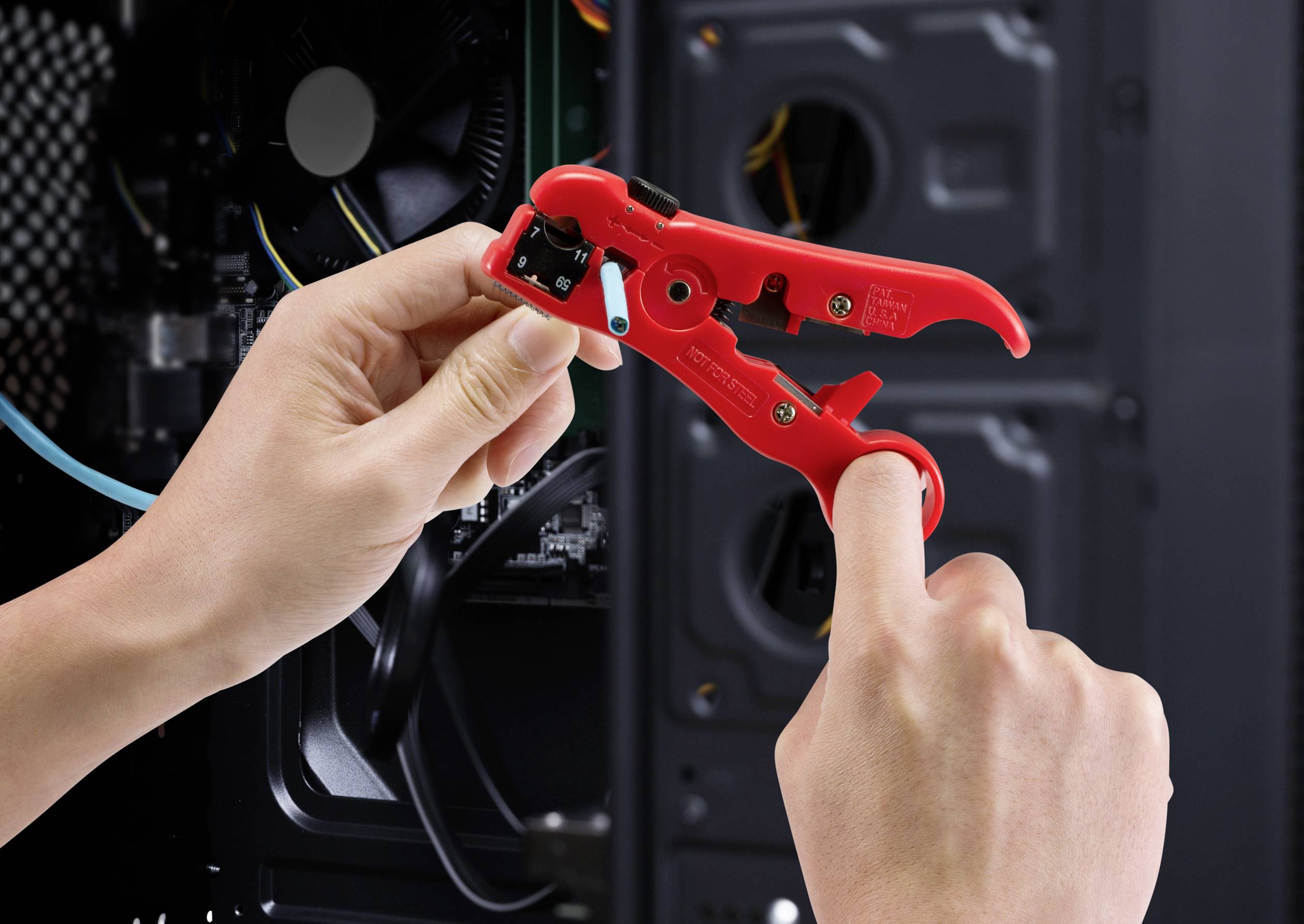 A person is cutting a cable with a red wire stripping pliers inside a computer case.