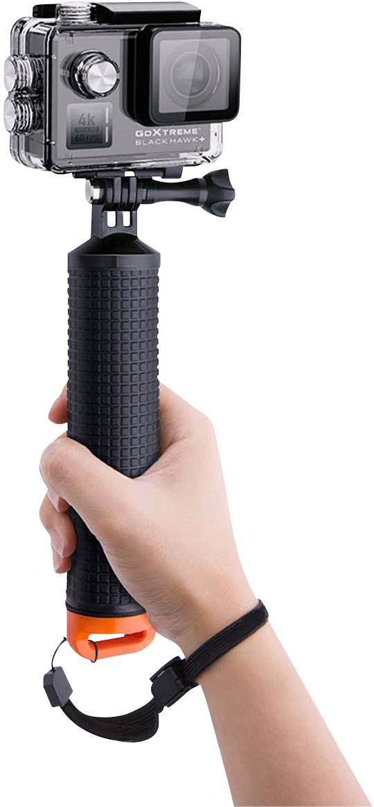 A hand is holding an action camera on a black grip with a wrist strap. The camera is in a waterproof housing.