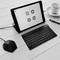 Tablet on table with video conferencing app open, keyboard and coffee mug beside it. Device ready for online meeting.