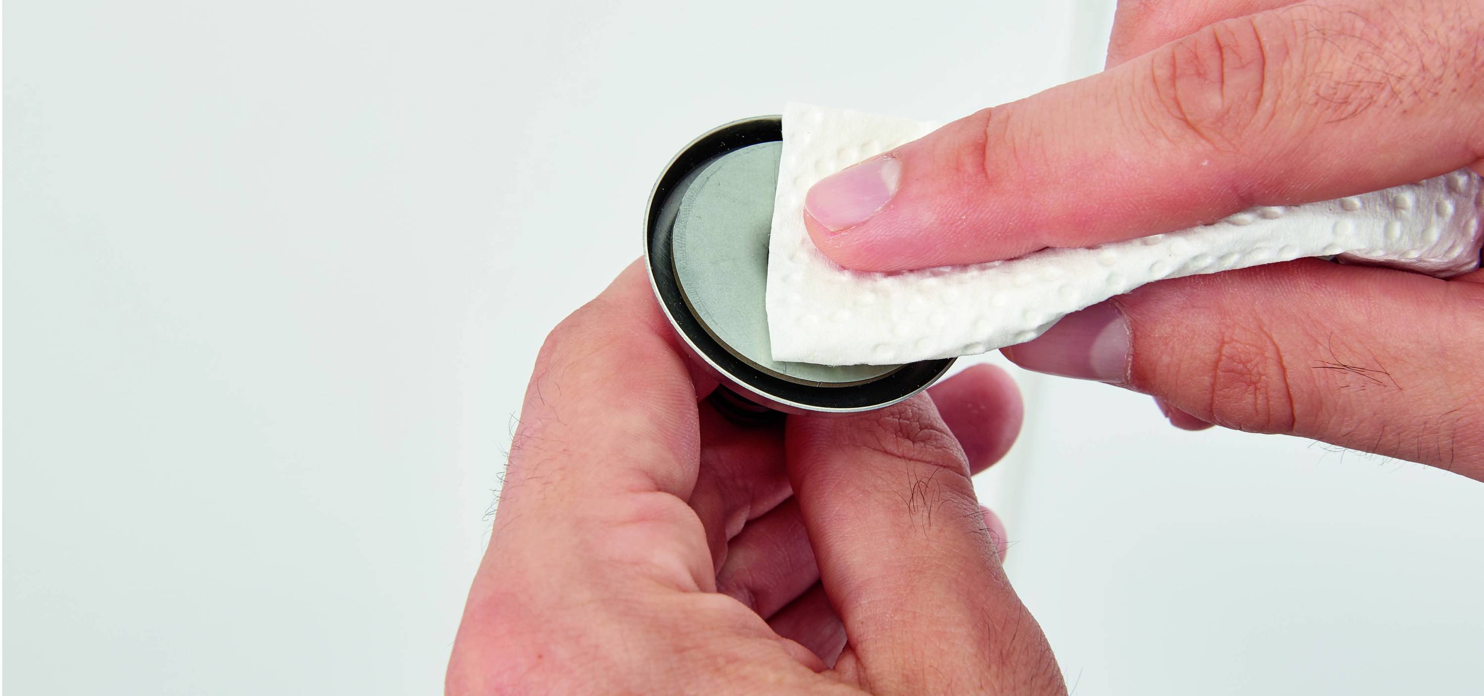 A hand is cleaning the surface of a coin with a cloth.