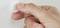 A hand presses a round white button against a wall.