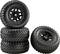 Four large black tyres with deep tread. Three stacked, one leaning to the side. Suitable for off-road vehicles.