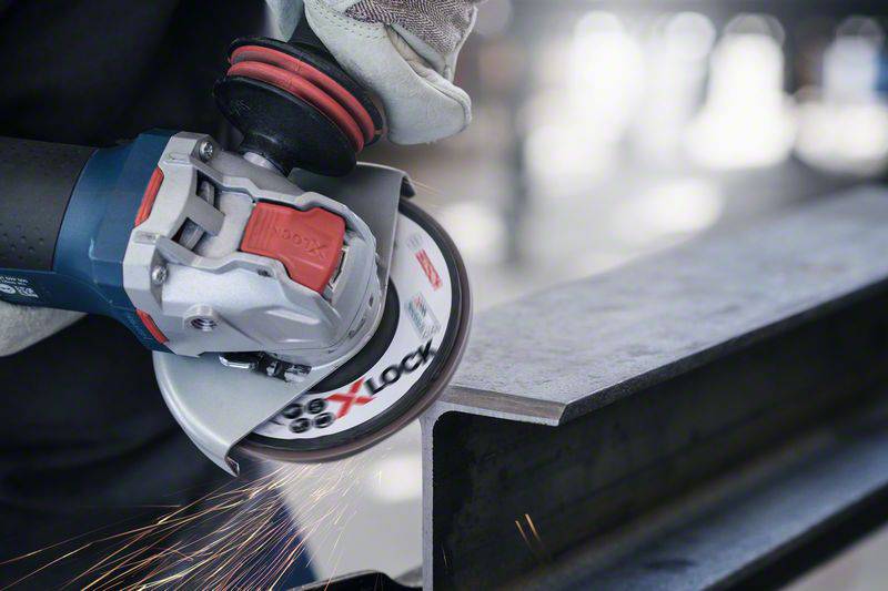 A person is working on a metal piece with an angle grinder, sparks flying. The scene demonstrates craftsmanship and precision in tool use.