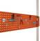An orange pegboard with various tools, including a hammer, pliers, and screwdrivers, neatly arranged and hung.