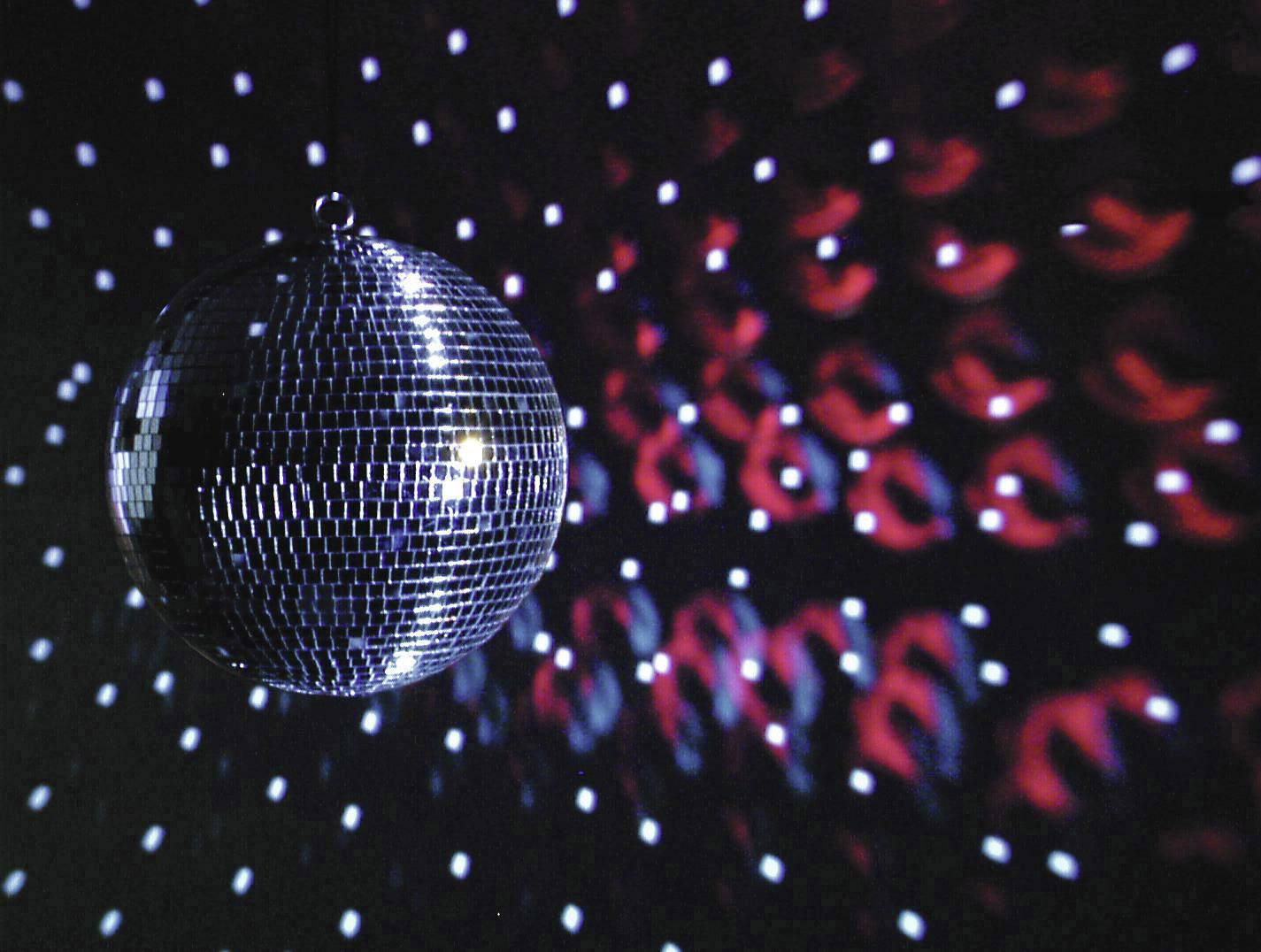 Disco ball throws many small points of light onto a dark wall, with red and white light reflections surrounding the ball.