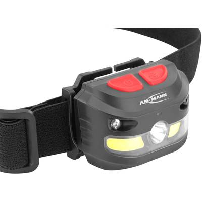 Black head torch with adjustable strap and two red buttons on top. 'Ansmann' brand name is visible. Ideal for outdoor activities.