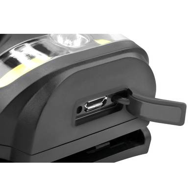 Close-up of a charging port on an electronic device. A plastic cover is opened to one side, revealing the connection.