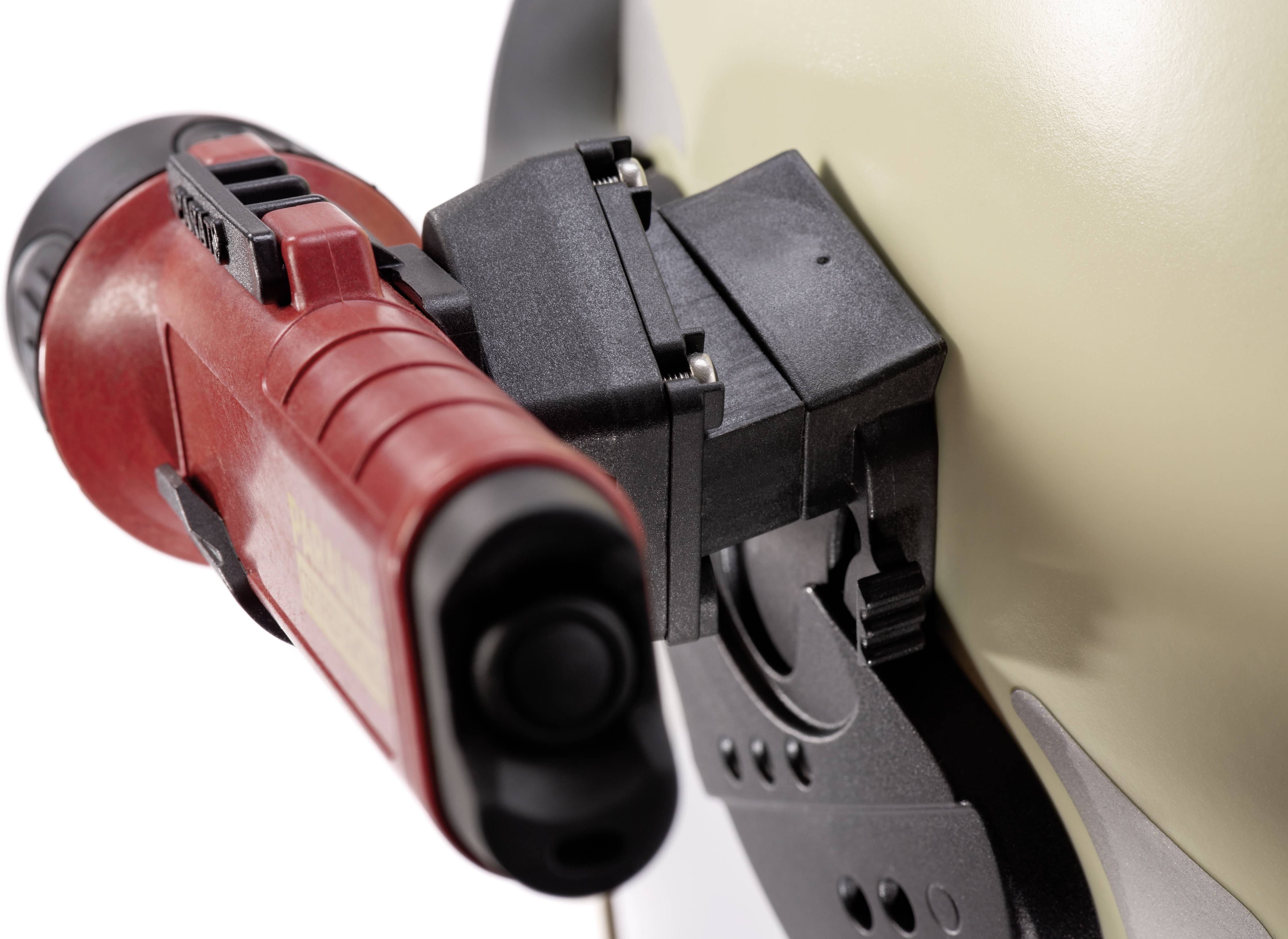 Power drill in close-up, focused on the red handle and chuck, secured to a light-coloured surface.