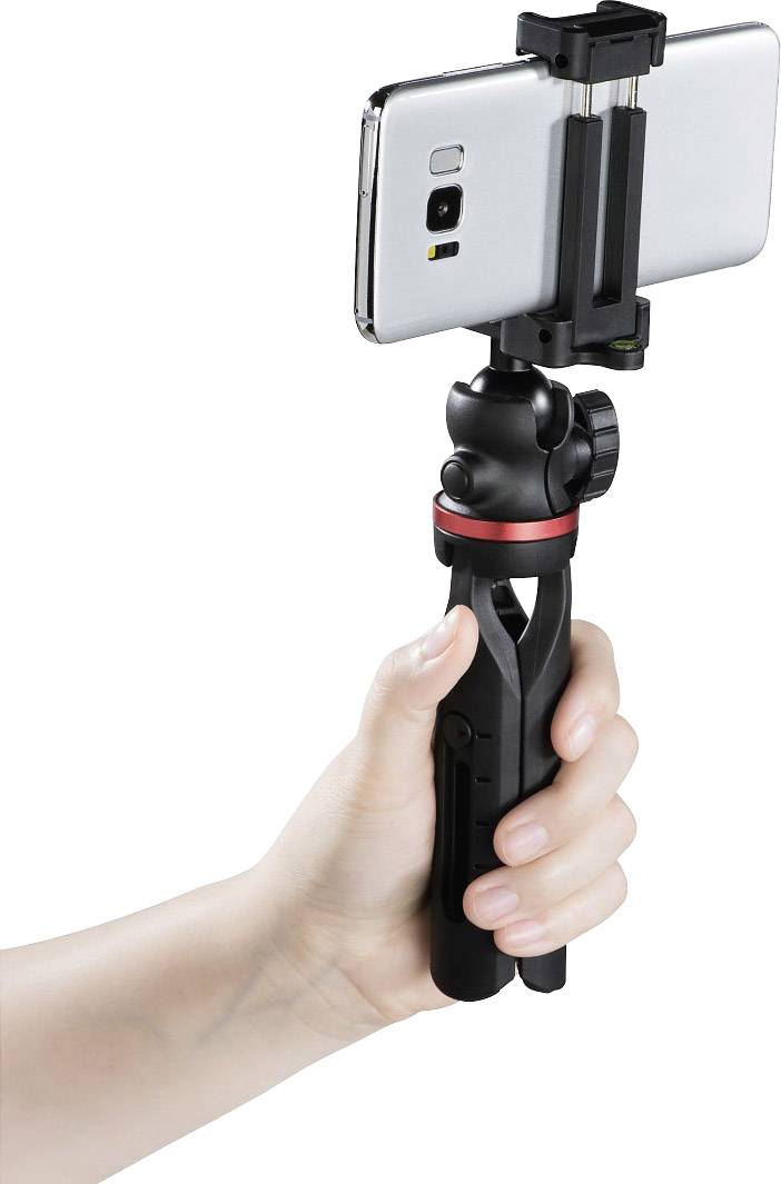 A hand is holding a small tripod with a smartphone attached. The tripod is black with a red accent.