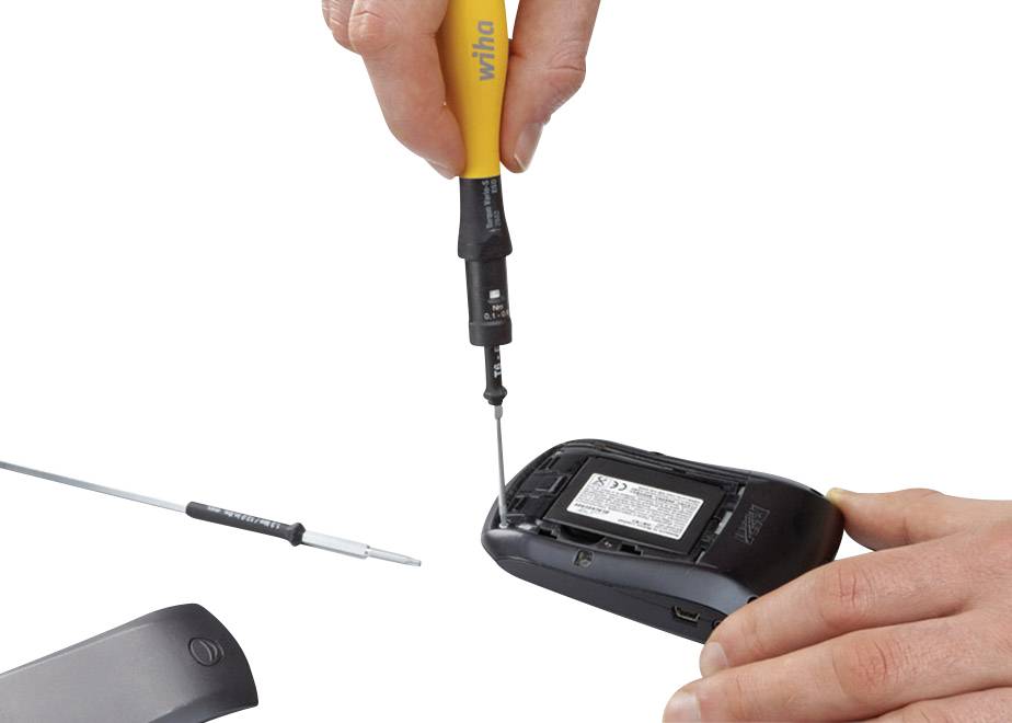 'A hand is holding a screwdriver and opening the back of a computer mouse. A second tool lies beside it on the table.'