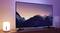 A television screen displays a landscape photograph of snow-capped mountains at sunset. Beside it stands a switched-on table lamp.