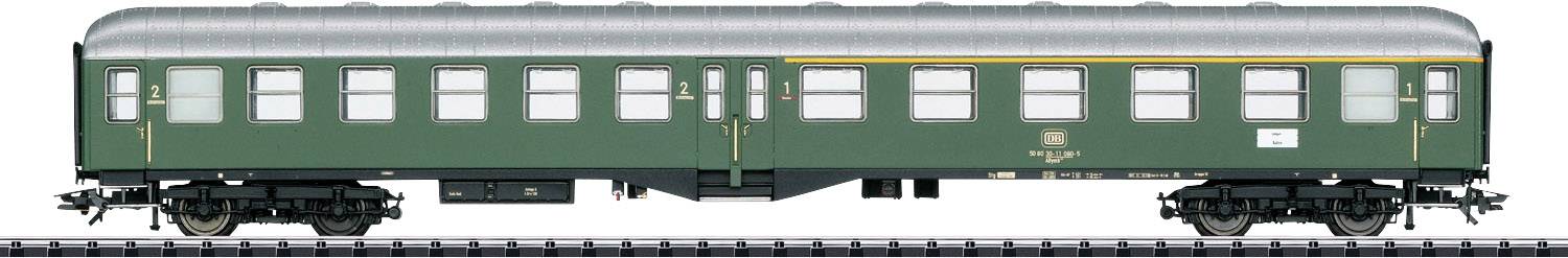 A green, classic railway passenger carriage with a silver roof and yellow stripes is standing on tracks.