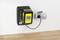 A black and yellow Kärcher charger is plugged into a wall socket. It is charging a battery.