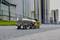 A miniature tanker truck drives along an empty street. High industrial buildings can be seen in the background.
