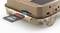 A memory card is inserted into a slot of a trail camera housing. The camera has a camouflaged design.