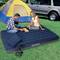 A woman and a man are playing a board game outdoors on an inflatable mattress in front of a tent and a car.