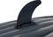 A black surfboard fin on a grey, ribbed surface.