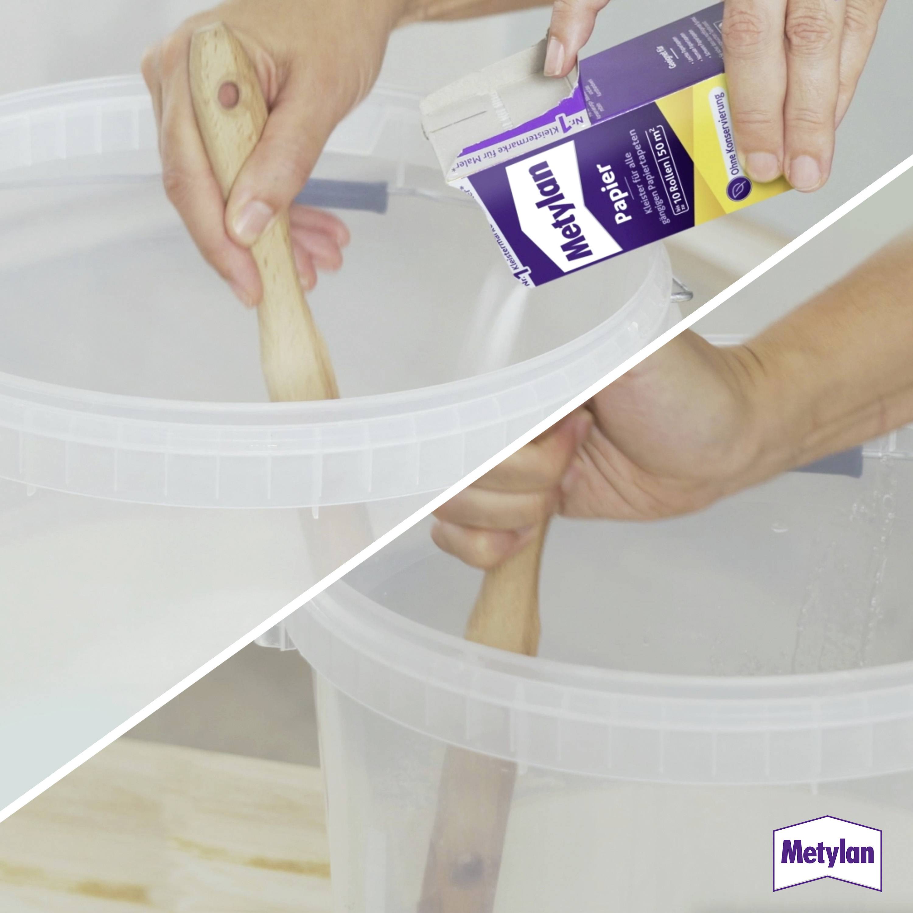 'Metylan Papier' adhesive box and wooden stick used to mix glue in a transparent container.