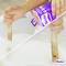 'Person stirring white paste in a container with a wooden stick while holding a Metylan adhesive product box.'