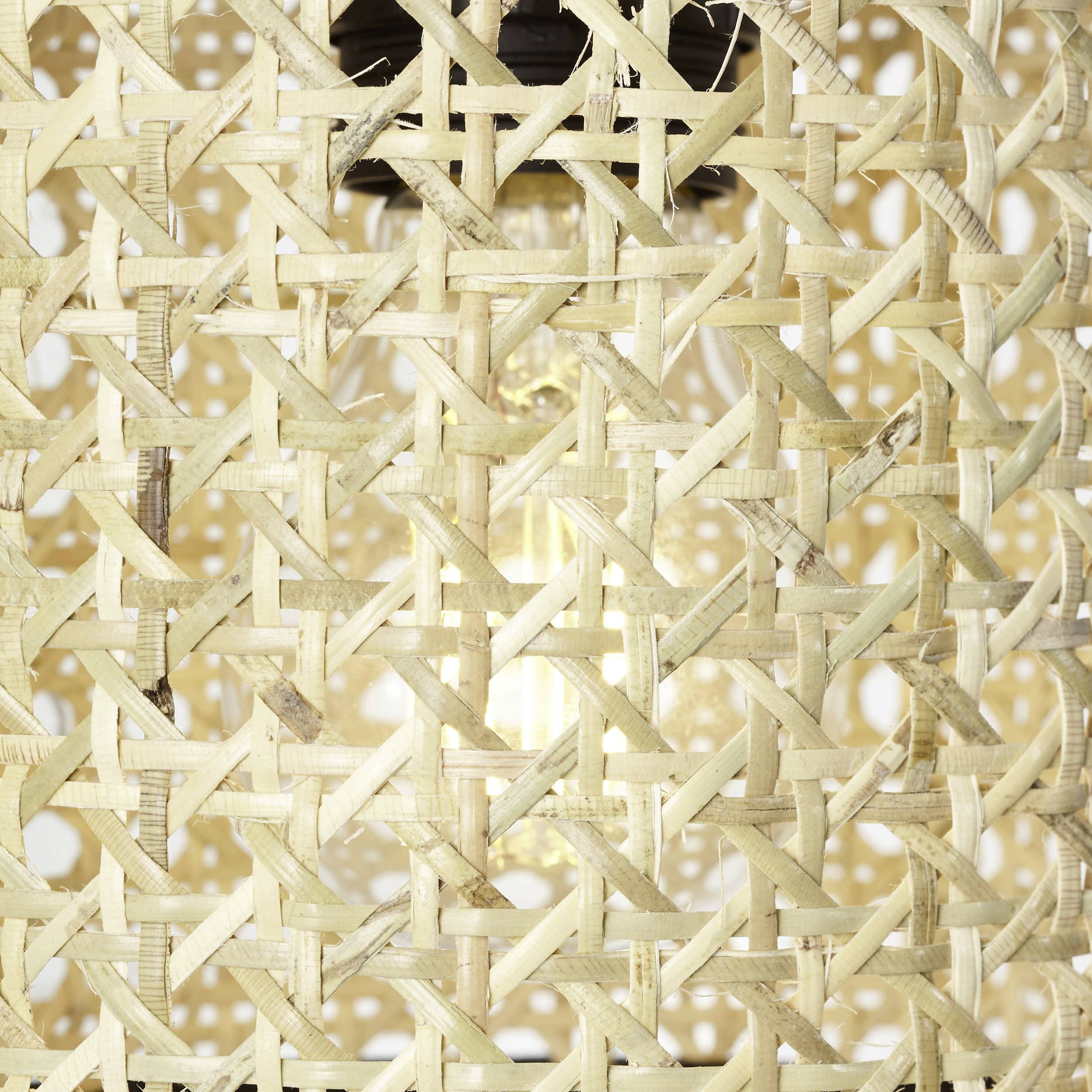 Woven bamboo lamp with visible light bulb inside, providing warm light and natural texture.
