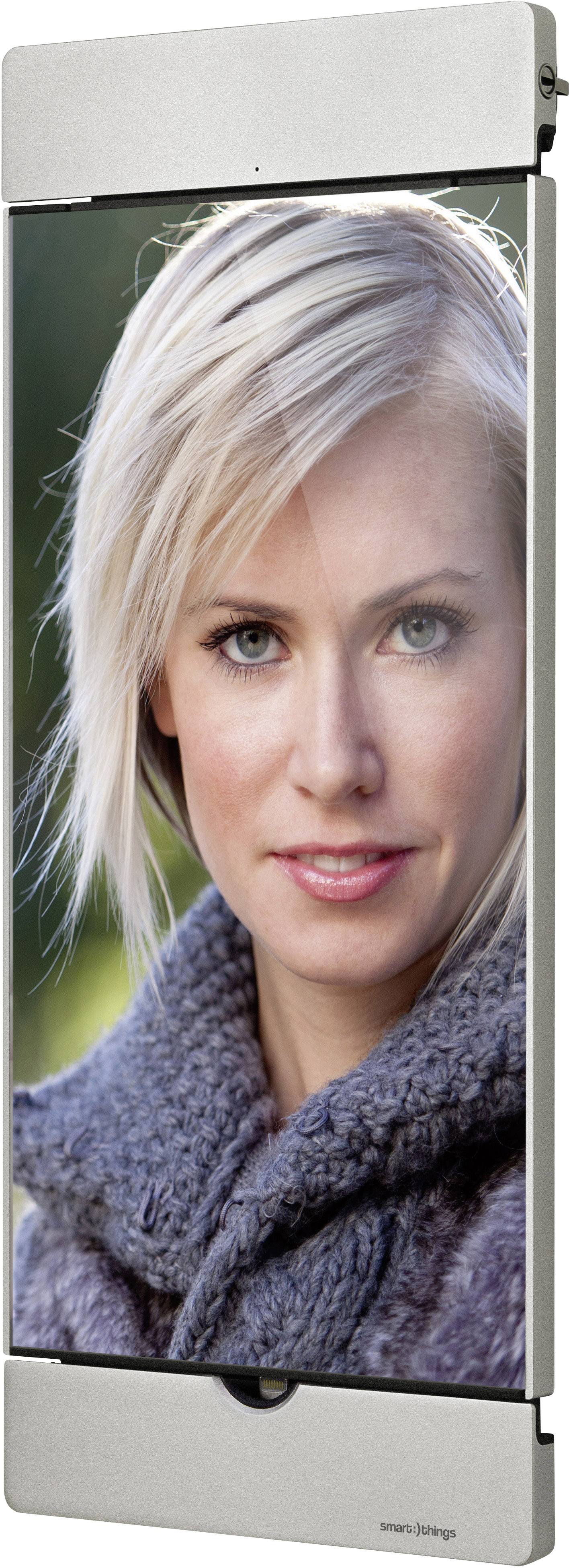 The image shows a person with blonde hair and a grey jumper, looking directly at the camera.