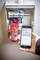 A person is holding a smartphone displaying a measurement of 2108 mA from a device in an open distribution cabinet.
