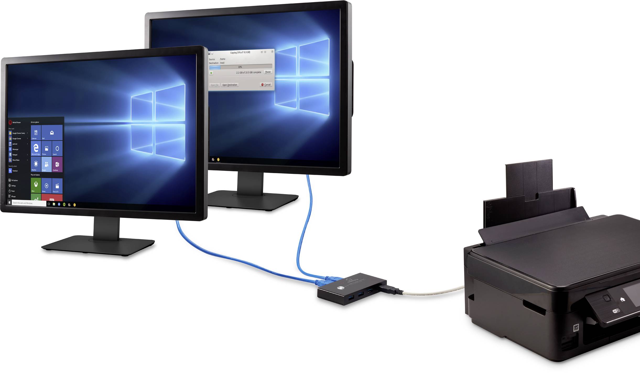 Two screens display the same computer desktop with Windows. A printer is connected via a device in between.