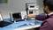 A man is operating an oscilloscope displaying waveforms on a workbench with electronic equipment and a laptop.