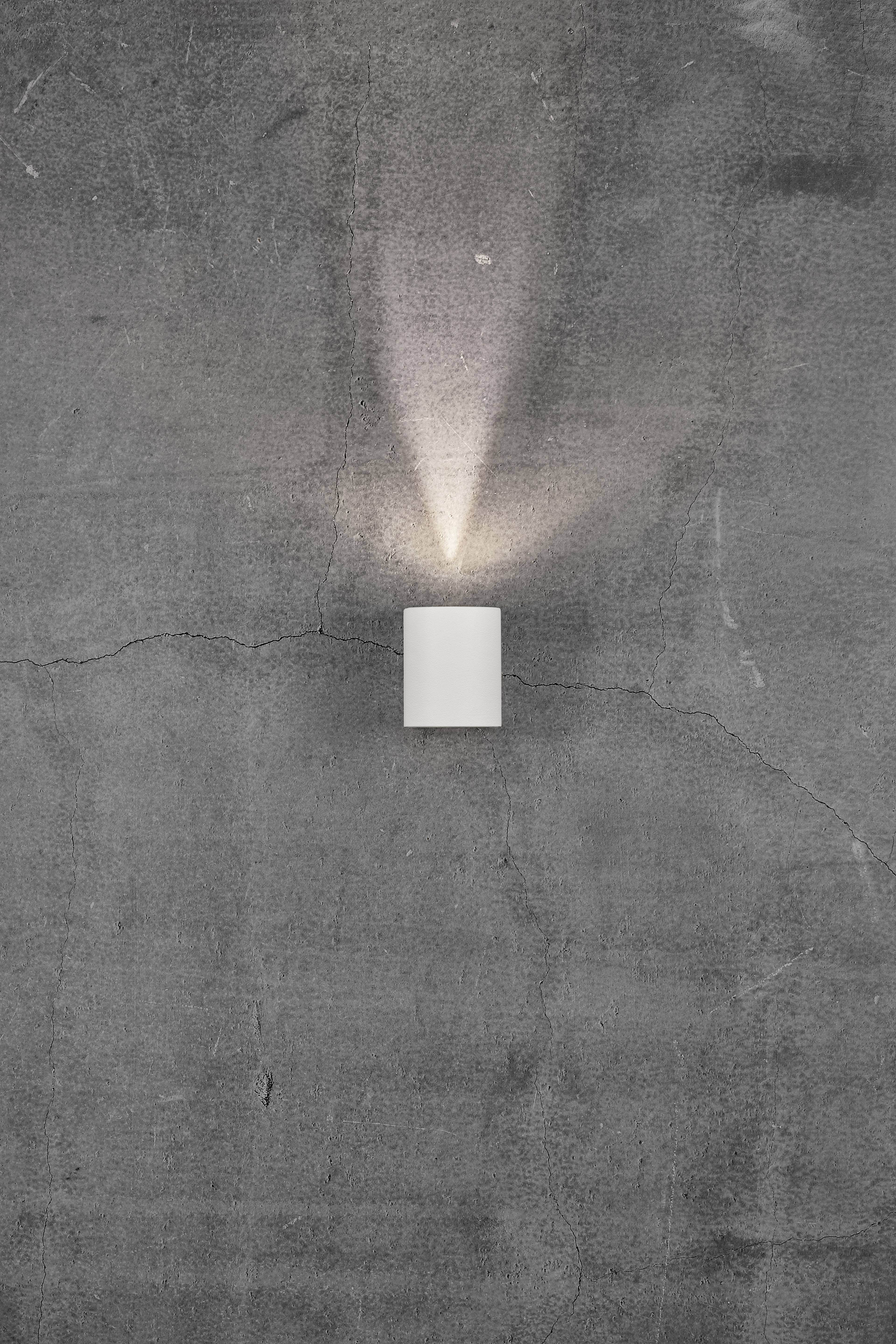 Wall light on a grey concrete wall, illuminating upwards and downwards.