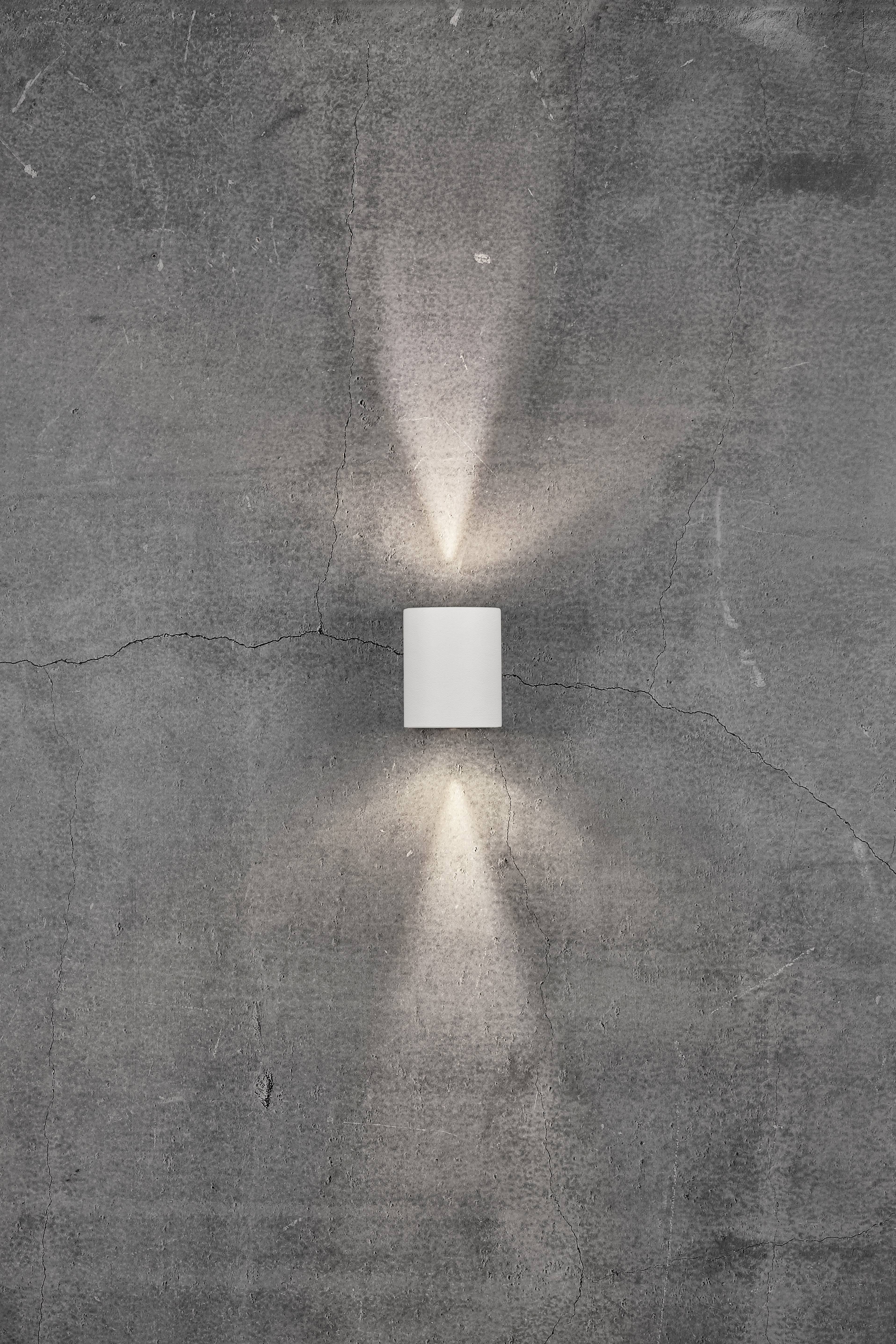 Wall light on a grey concrete wall, illuminating upwards and downwards.