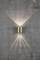 Wall light mounted on a concrete wall, projecting light rays upwards and downwards. Modern design with brushed brass.