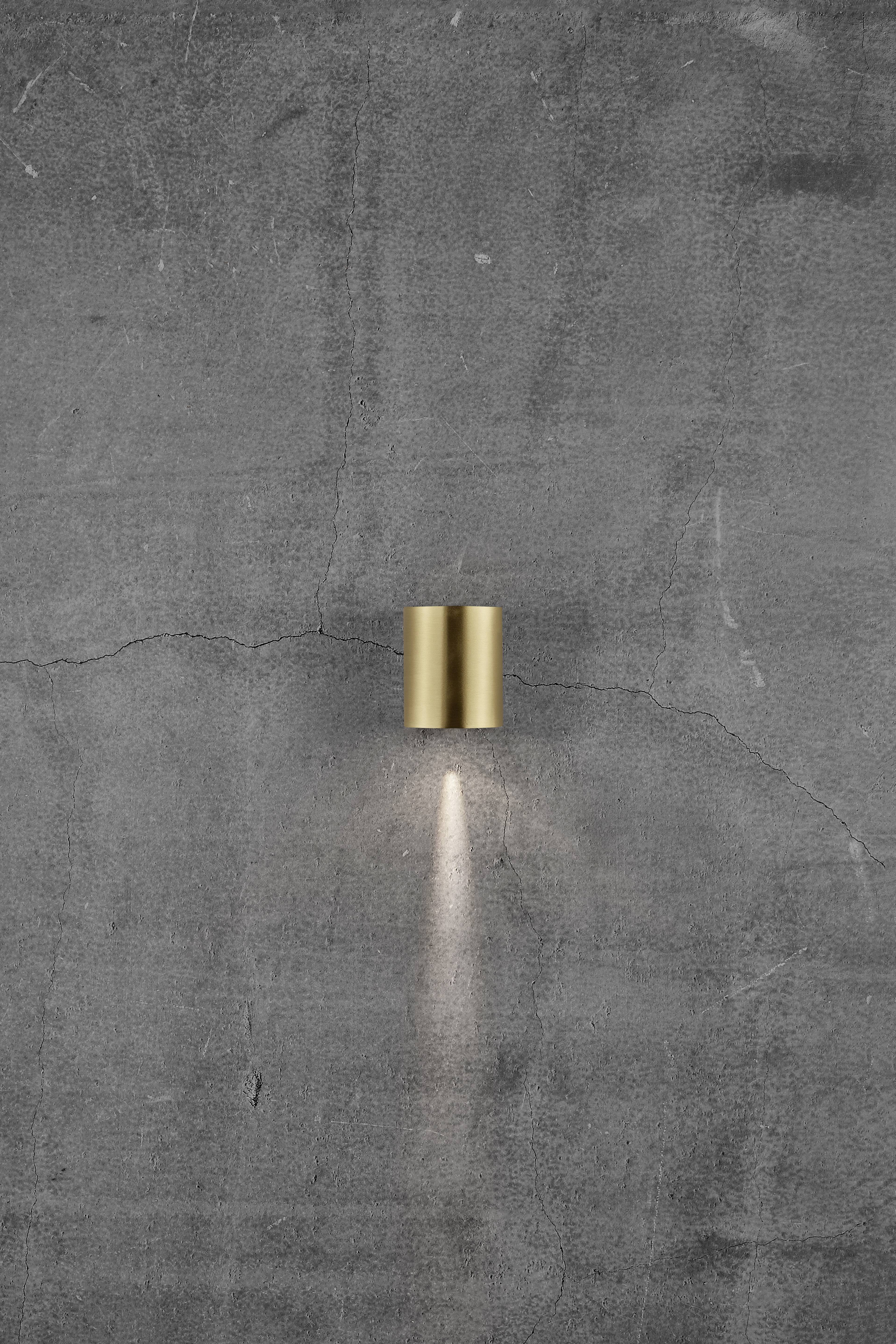 A golden wall light radiates downwards onto a grey, slightly cracked concrete surface.