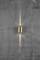 A golden wall light on a grey concrete wall radiates soft light upwards and downwards, creating a stylish atmosphere.