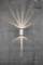 Silver wall light on a grey, cracked wall, radiating warm light upwards and downwards, creating soft light patterns.