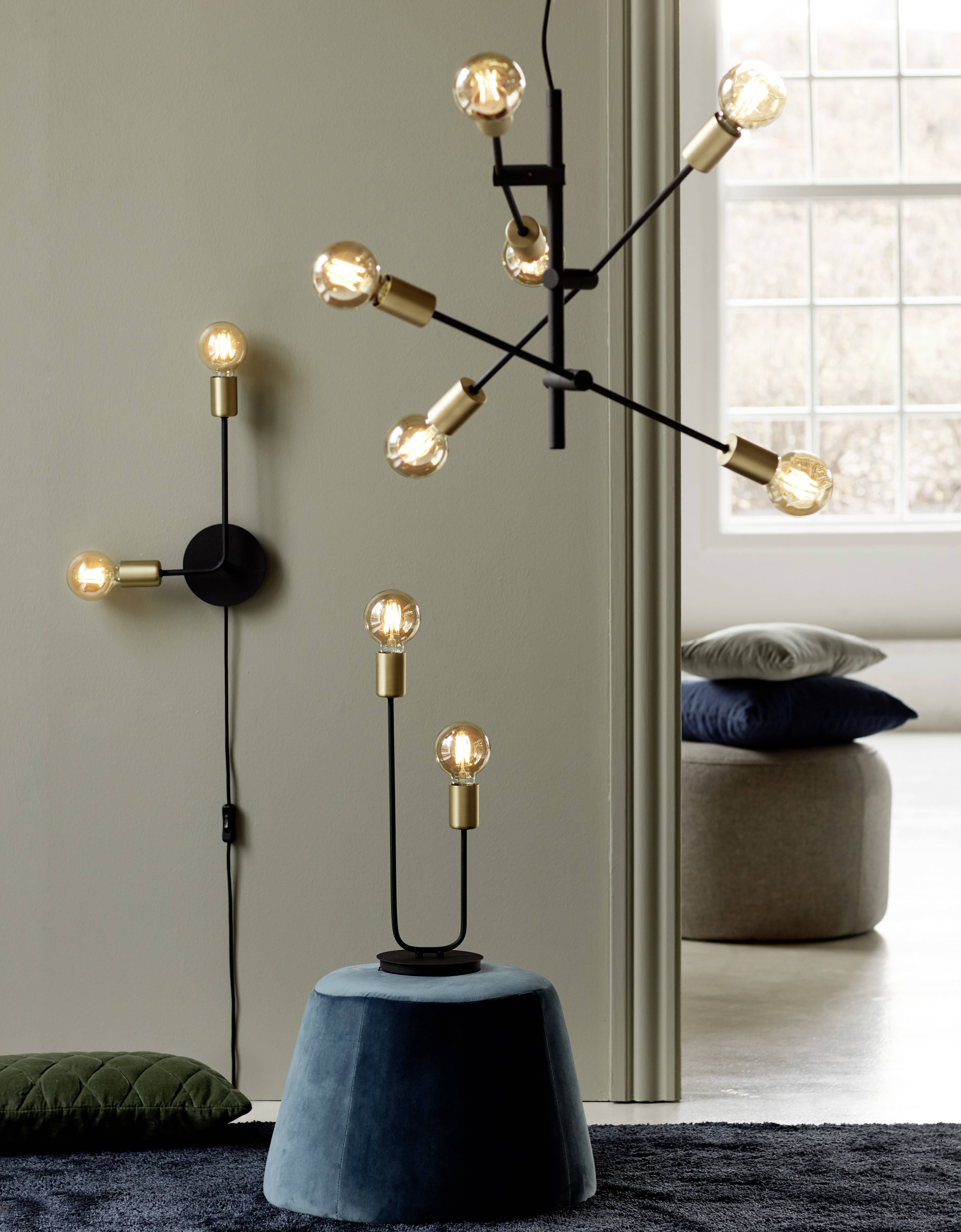 Several stylish, modern lamps with round light bulbs in a minimally decorated room. They hang from the ceiling and stand on the floor.