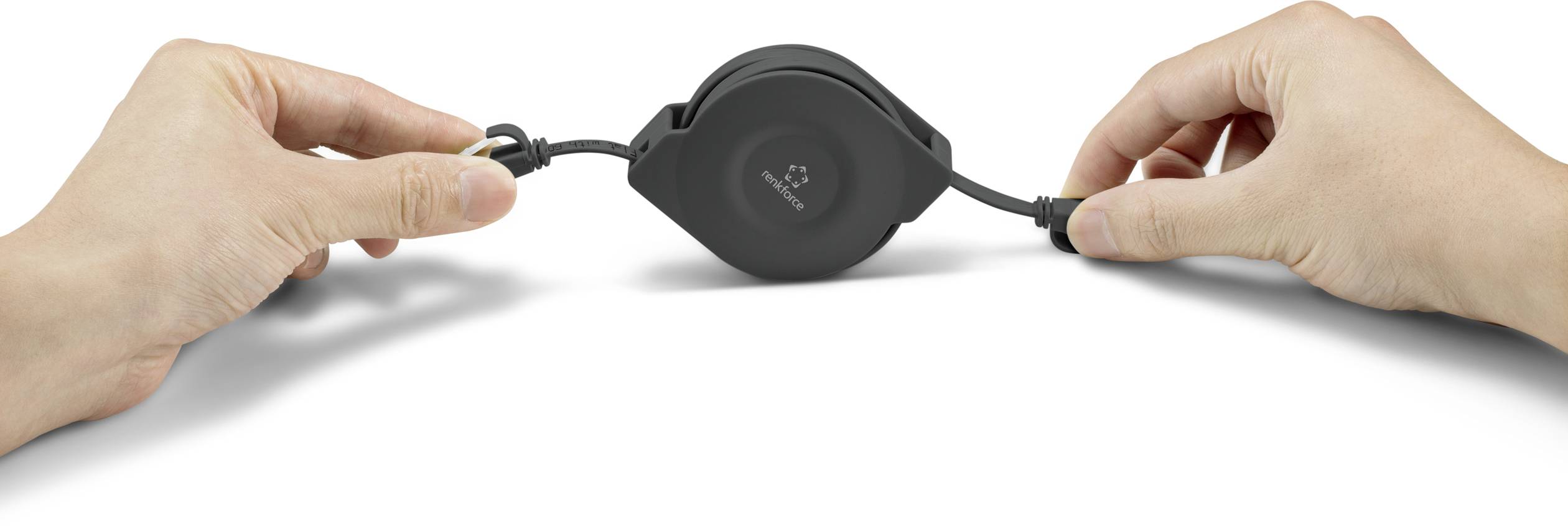 Two hands are pulling on a black, retractable cable reel. One hand is holding the plug, the other the housing.