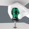 A hand is holding a green screwdriver with a black handle, from the brand 'Wera', in a twisting motion.