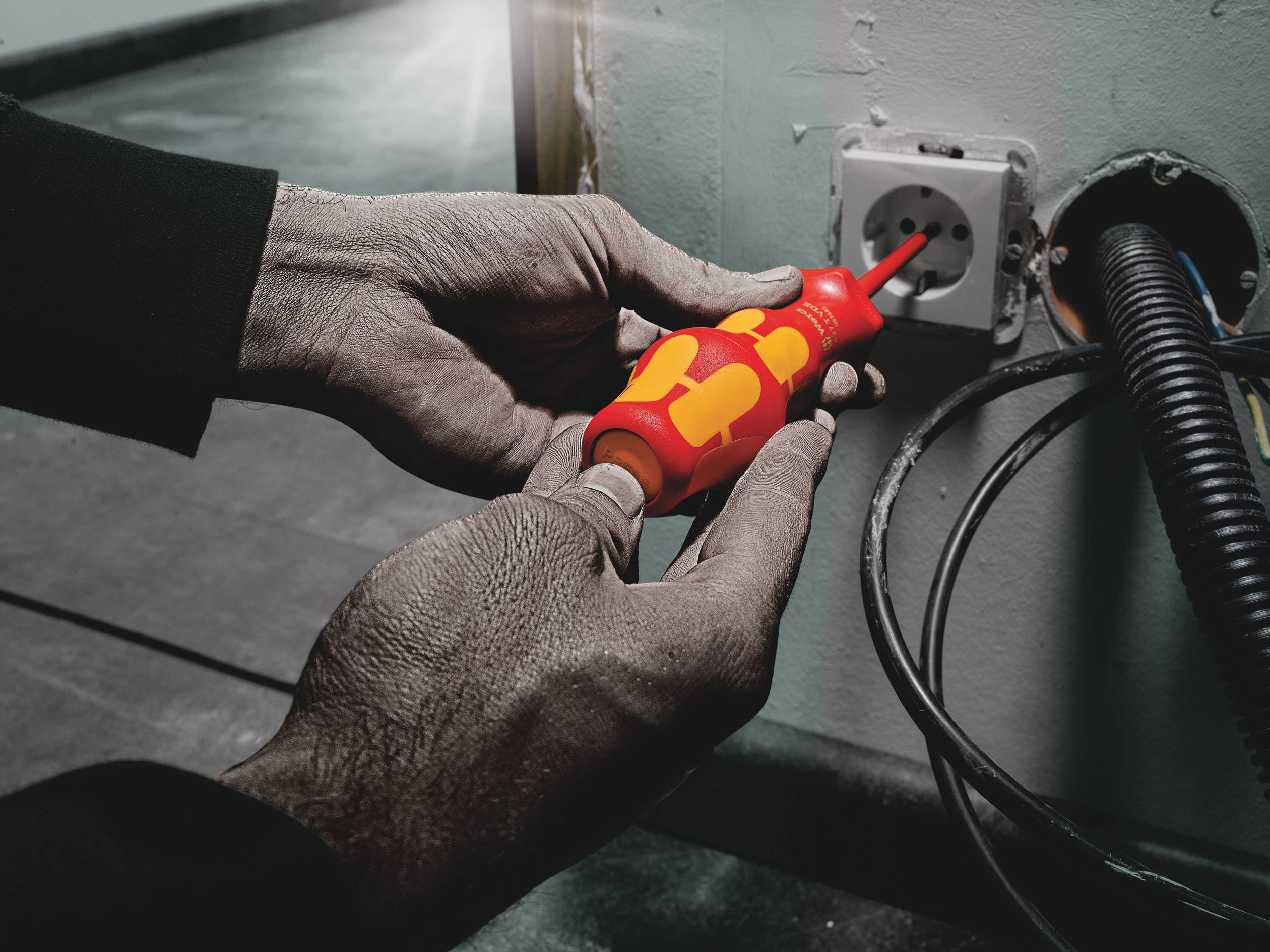 A person is testing a socket with a voltage tester. Cables are leading to the socket.
